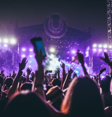 Concert crowd with raised hands under purple stage lights