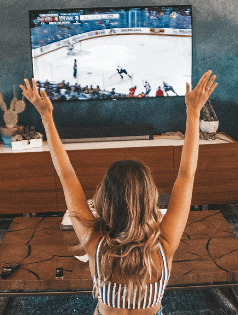 Juichende fan voor een tv met ijshockey, tevreden kijkers