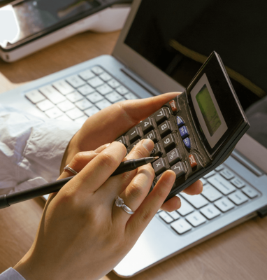 Hands using a calculator and laptop, illustrating MaelStrom Live pricing and cost savings