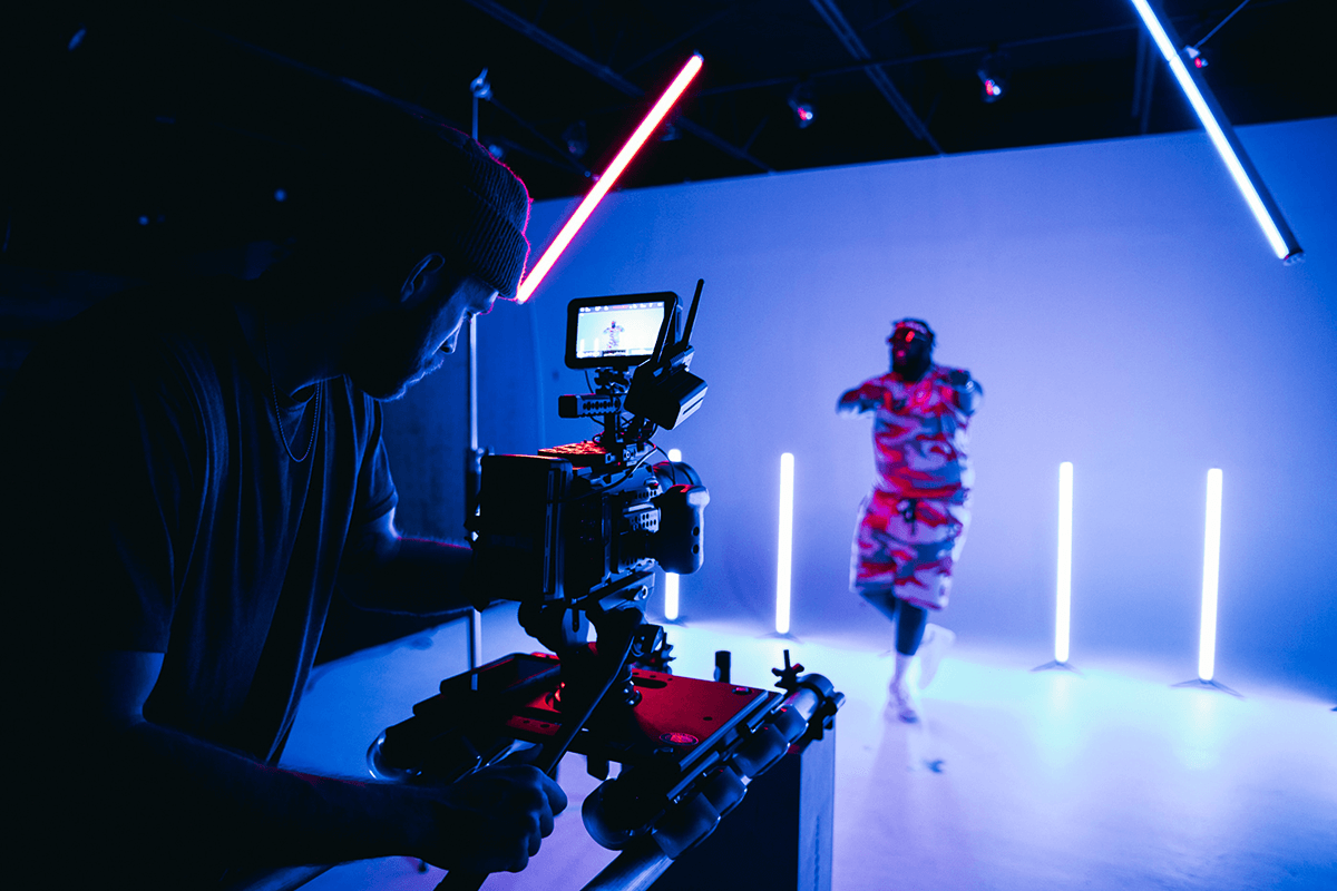 Camera die een danseres filmt in een studio met neonlicht