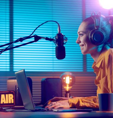 Woman with headphones at a studio microphone recording a podcast or radio show