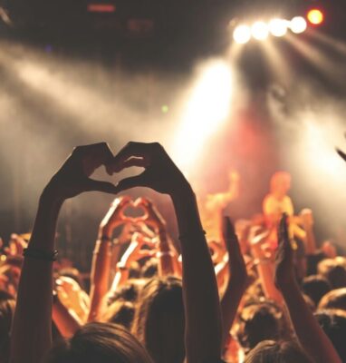 Concert crowd making heart shapes with their hands, cover for article on direct contact with fans